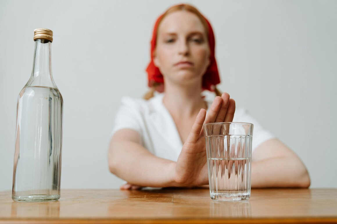 Mensch mit einem Glas Wasser und einem Weinglas auf dem Tisch, symbolisch abwägend